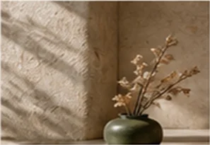 A quiet corner with a green vase of dried blossoms against limewashed walls
