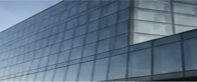 Glass facade of a modern office tower against a pale sky