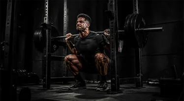Athlete at the bottom of a barbell back squat in the power rack